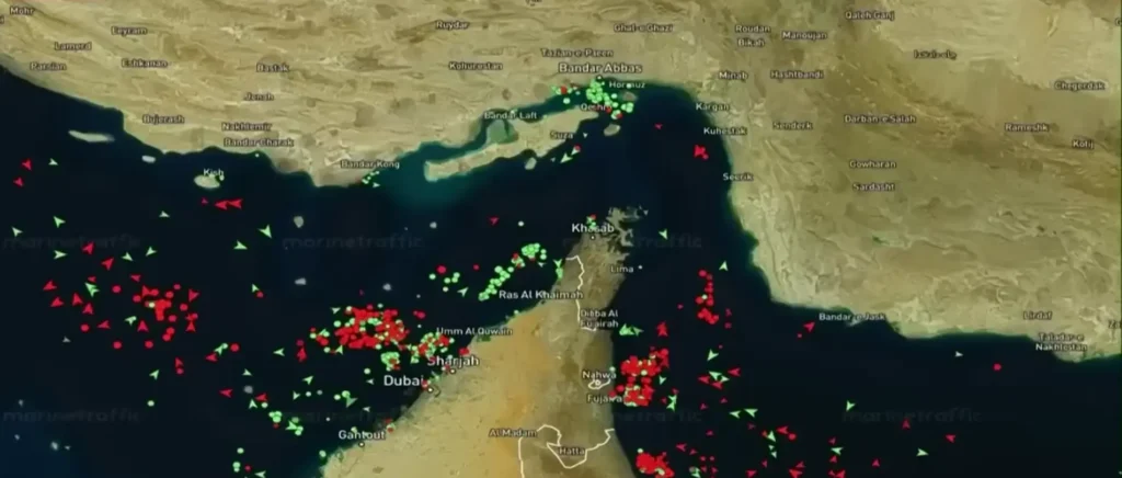 A marine traffic map of the Strait of Hormuz showing numerous red and green vessels.