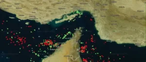 A marine traffic map of the Strait of Hormuz showing numerous red and green vessels.