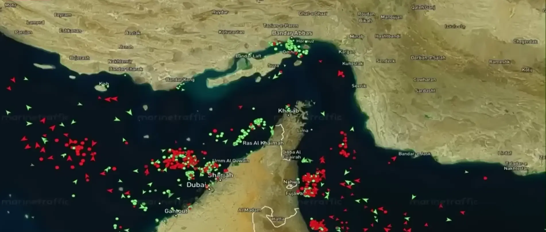A marine traffic map of the Strait of Hormuz showing numerous red and green vessels.