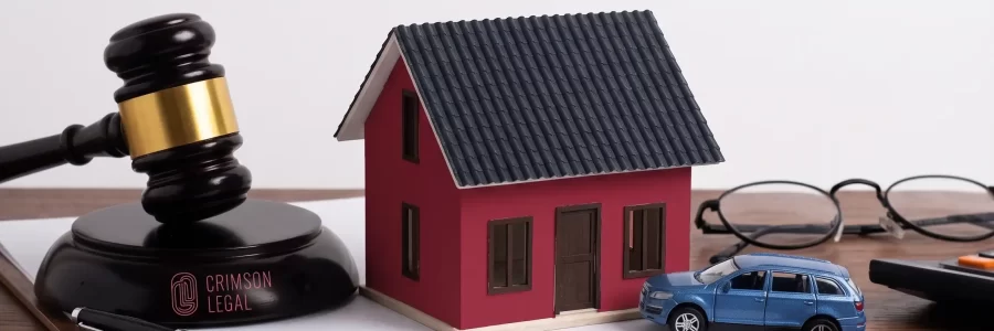 A professional legal scene at a wooden desk depicting assets such as a model house and a car, with Crimson Legal's gavel to discuss 'Family and Real Estate in Dubai'.