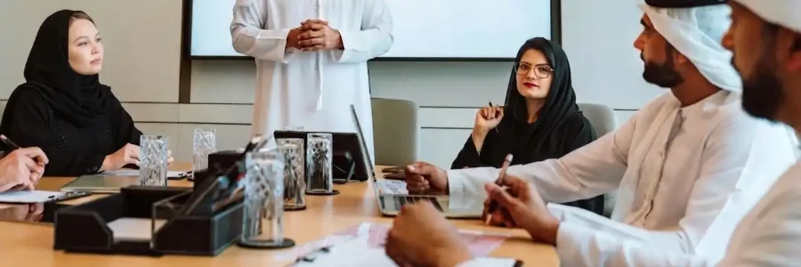 An Emirati man presents to professionals in traditional Gulf attire around a conference table before a Crimson Legal display screen.